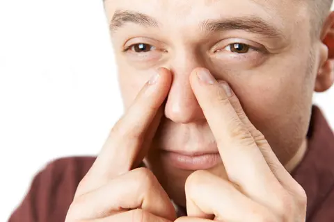 Man massaging nose for sinus pressure