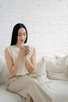 Woman relaxing with mug on white sofa