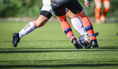 Two soccer players contesting ball on grass