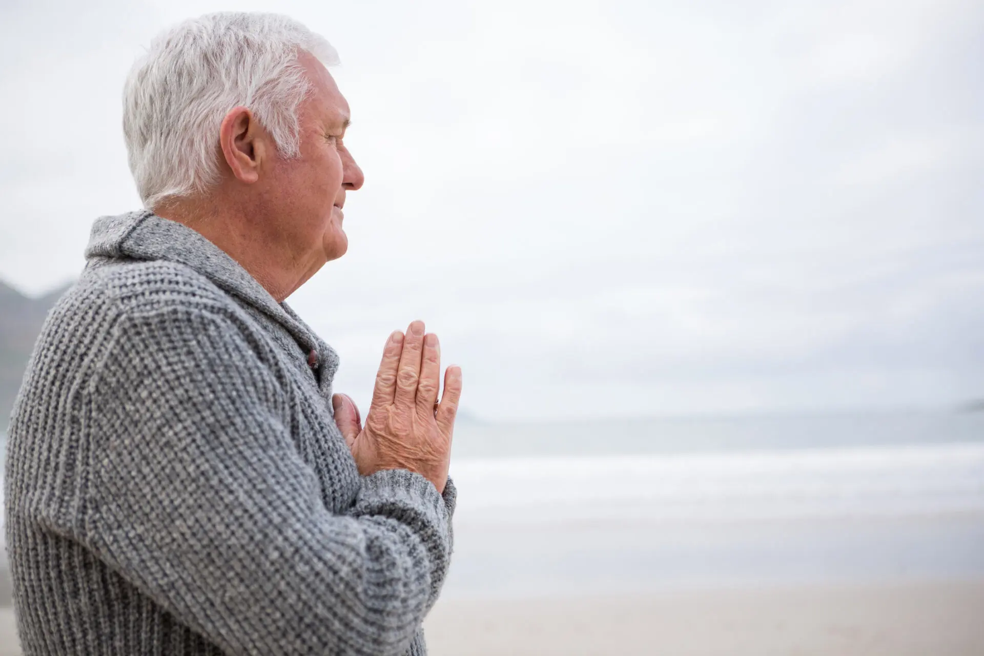 Elderly man meditating on beach