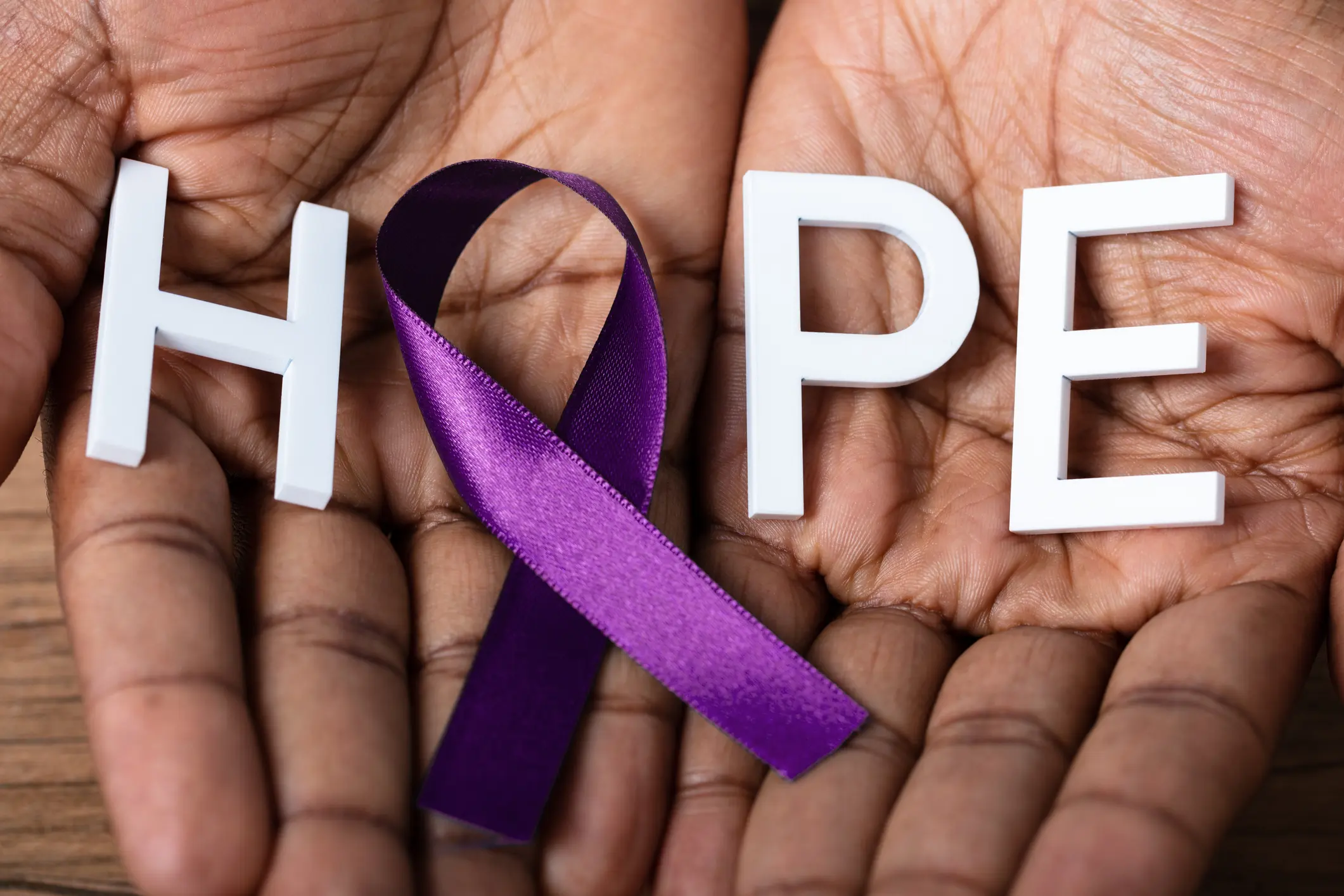 Hands holding HOPE with purple ribbon