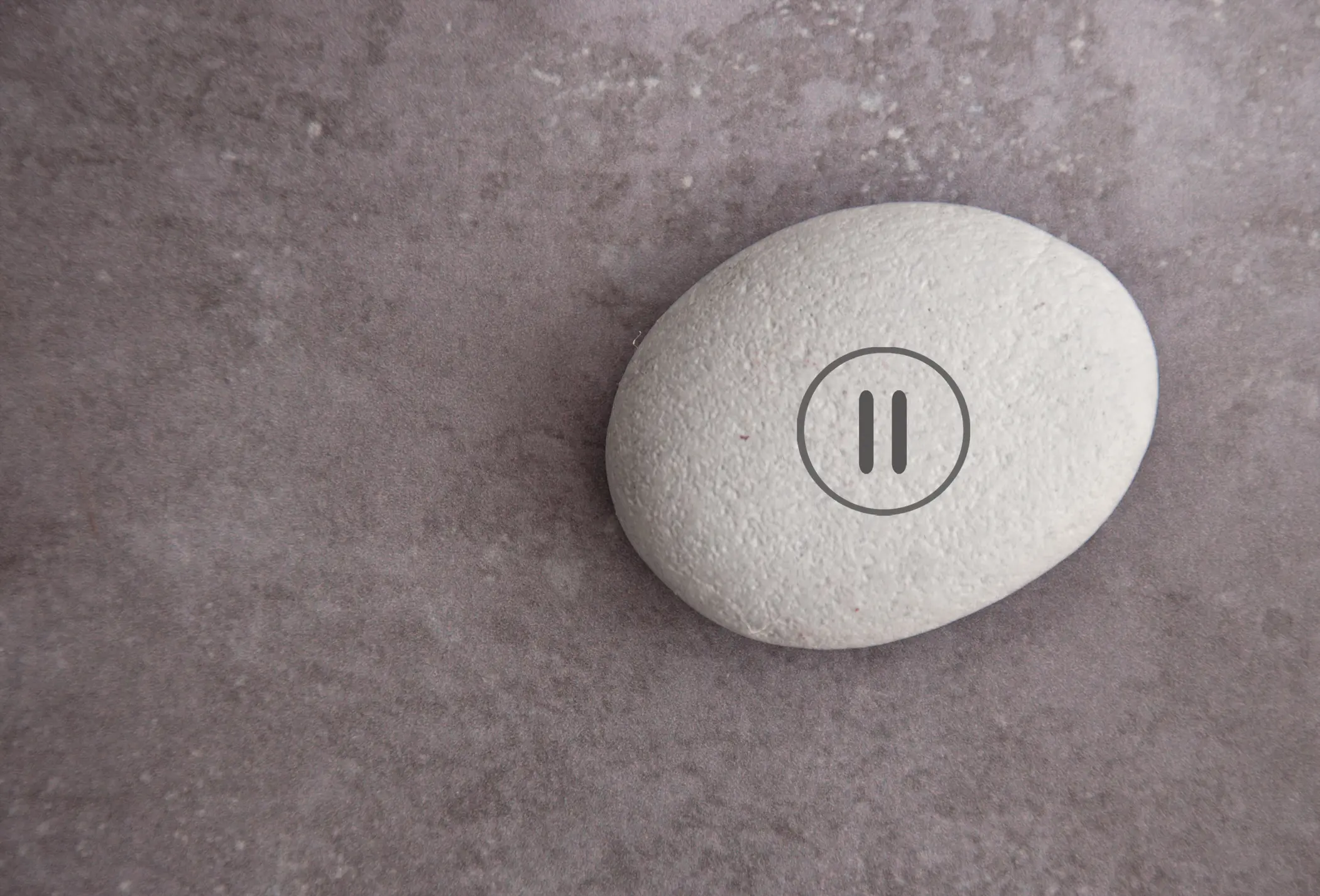 Smooth white pebble with pause symbol