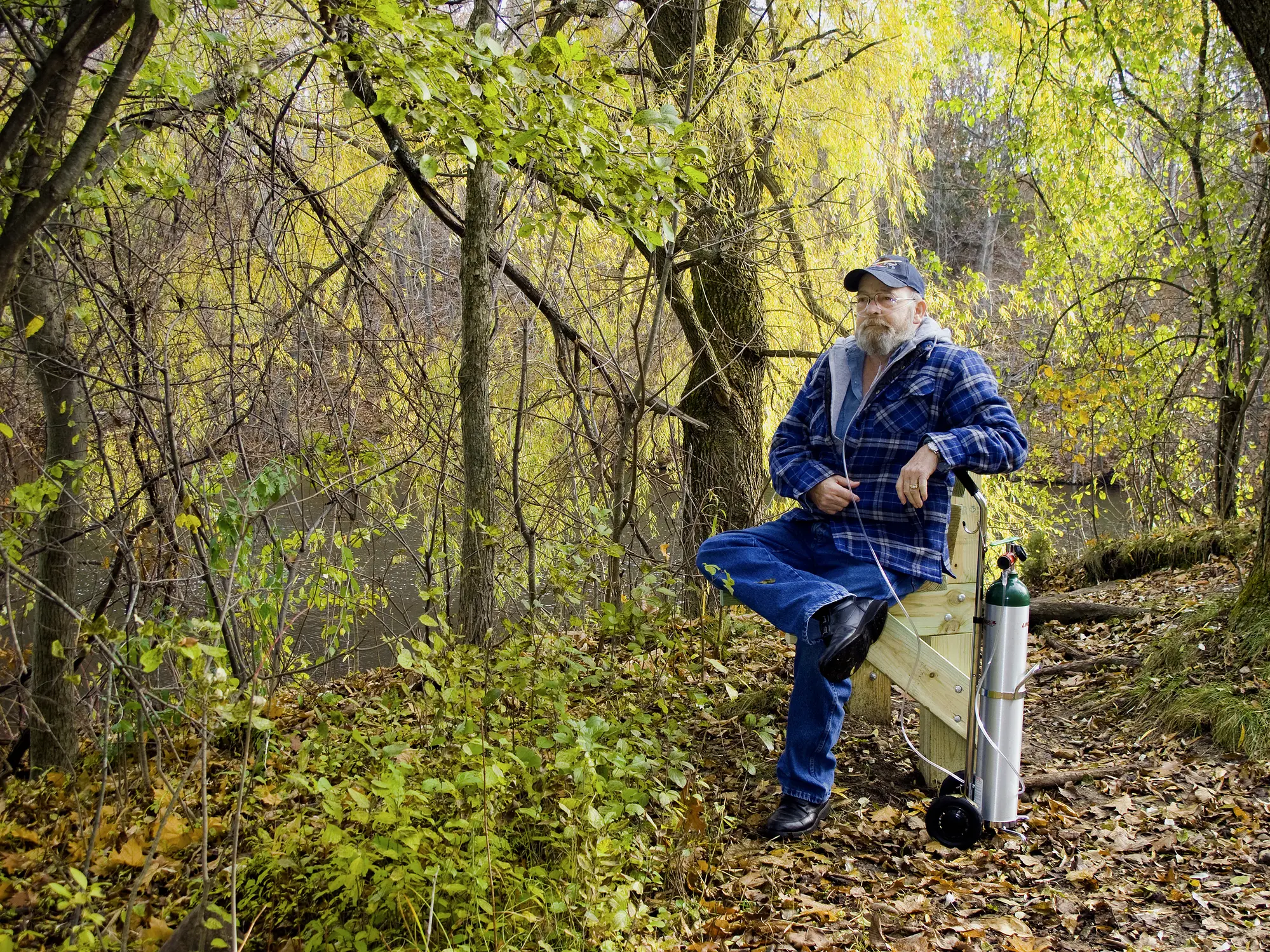 Man with portable oxygen tank sitting outdoors