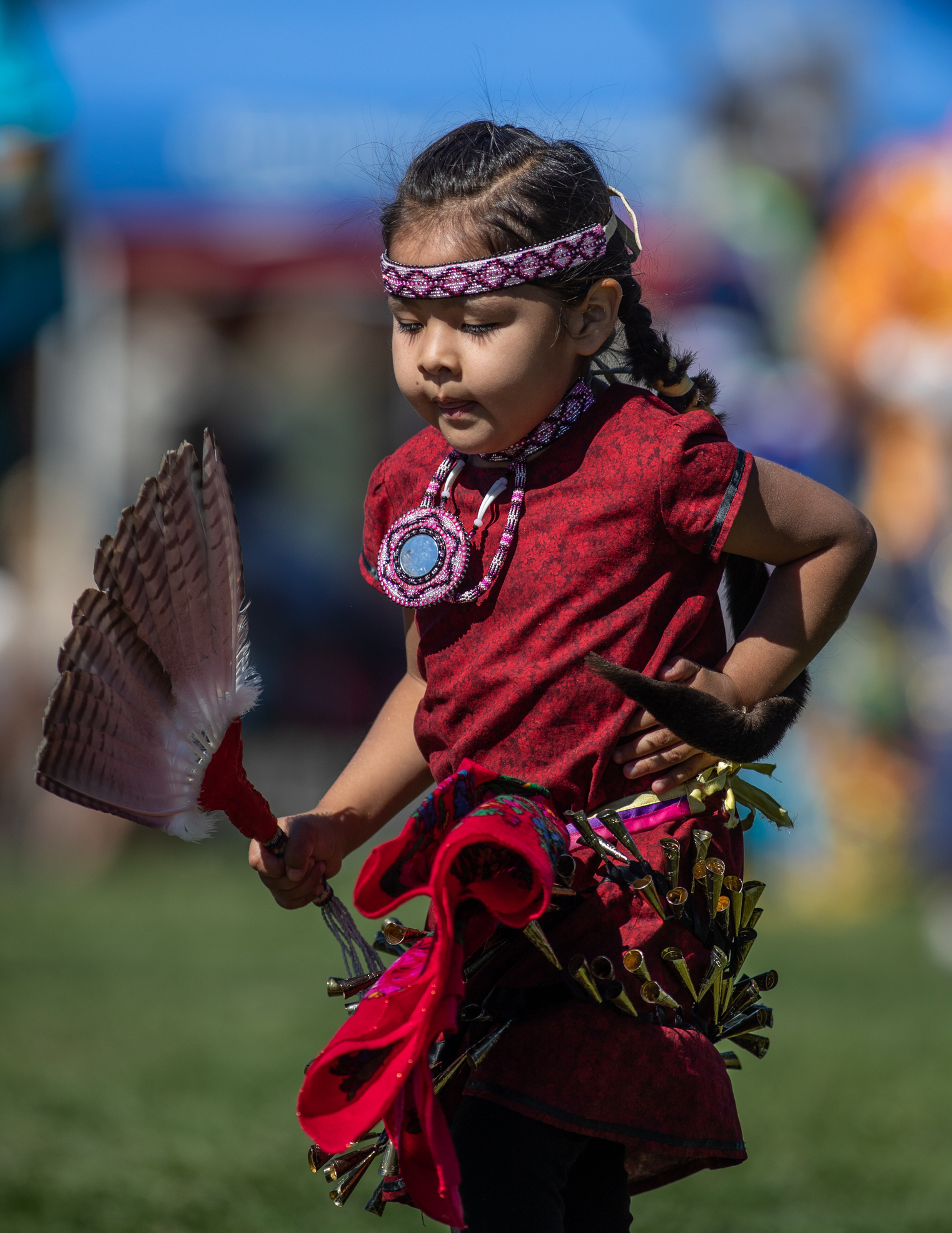 Child dancer in red regalia holding fan
