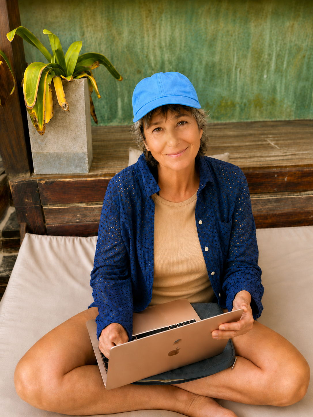 Smiling person in blue cap using laptop